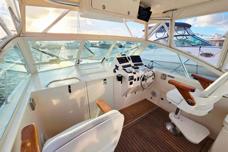 Slide: The Image of 2007 Carolina Classic 28 Express boat cockpit with helm, wooden accents, and marina view. - 21