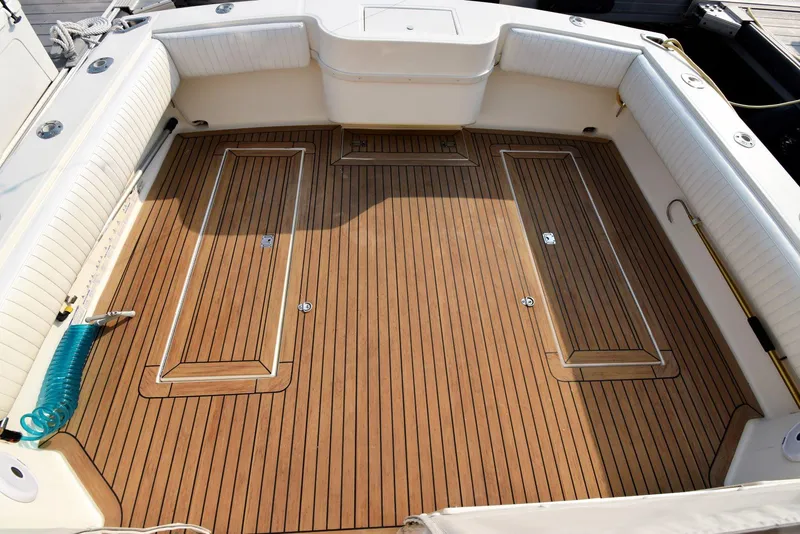 Slide: The Image of 2007 Carolina Classic 28 Express boat deck with teak flooring and white cushioned seating. - 8