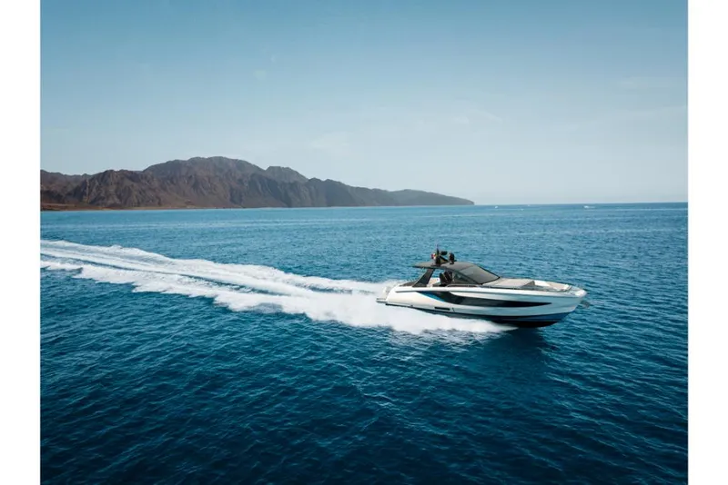 Slide: The Image of 2023 Azimut Verve 42 yacht cruising on open blue water near a mountainous coastline. - 2