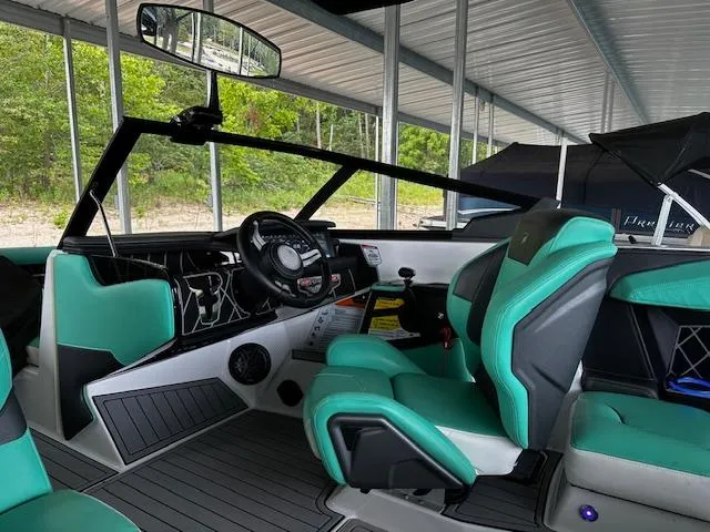 Slide: The Image of 2021 Nautique GS20 boat interior with teal and black seating under a covered dock. - 11