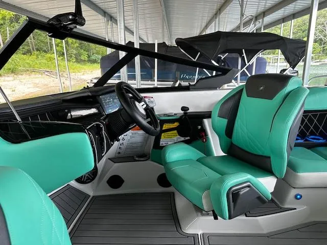 Slide: The Image of 2021 Nautique GS20 boat interior with teal and black seating, steering wheel, and dashboard. - 12