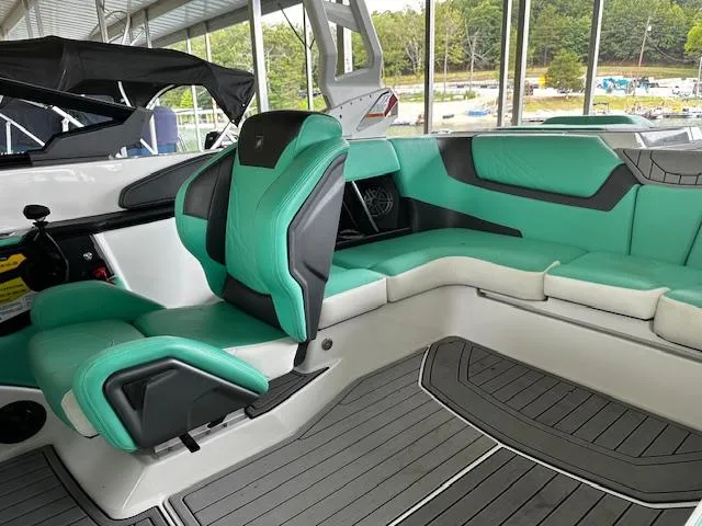 Slide: The Image of 2021 Nautique GS20 boat interior with green and black seating, docked at marina. - 13