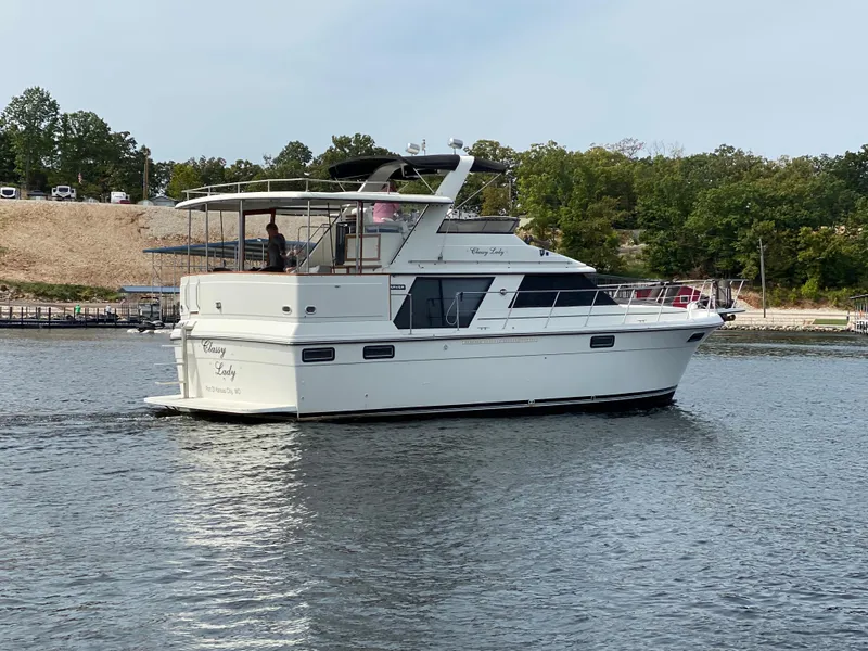 Slide: The Image of 1986 Carver 4207MY yacht cruising on a lake with a scenic background. - 11