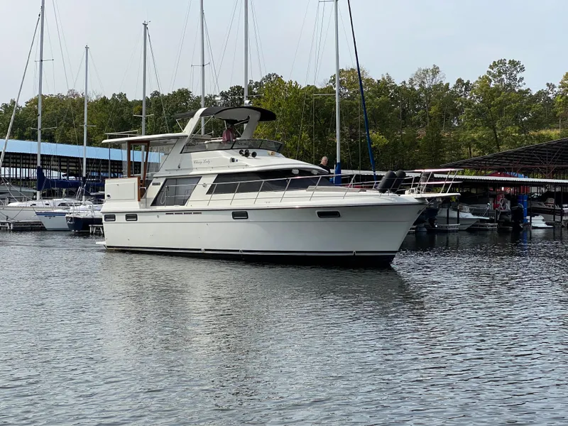Slide: The Image of 1986 Carver 4207MY yacht docked in a marina with sailboats in the background. - 13