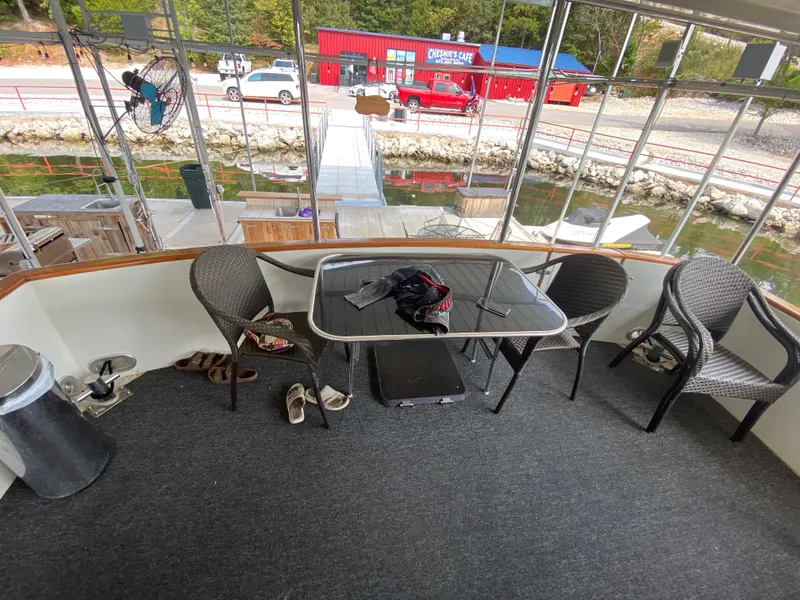 Slide: The Image of 1986 Carver 4207MY boat deck with table and chairs, docked near a red building. - 34