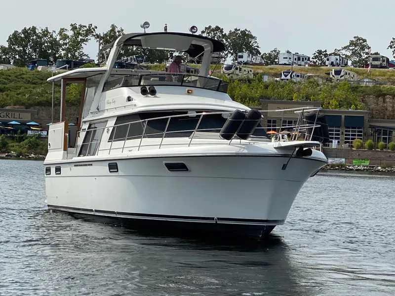 Slide: The Image of 1986 Carver 4207MY yacht cruising on a lake near a marina. - 4