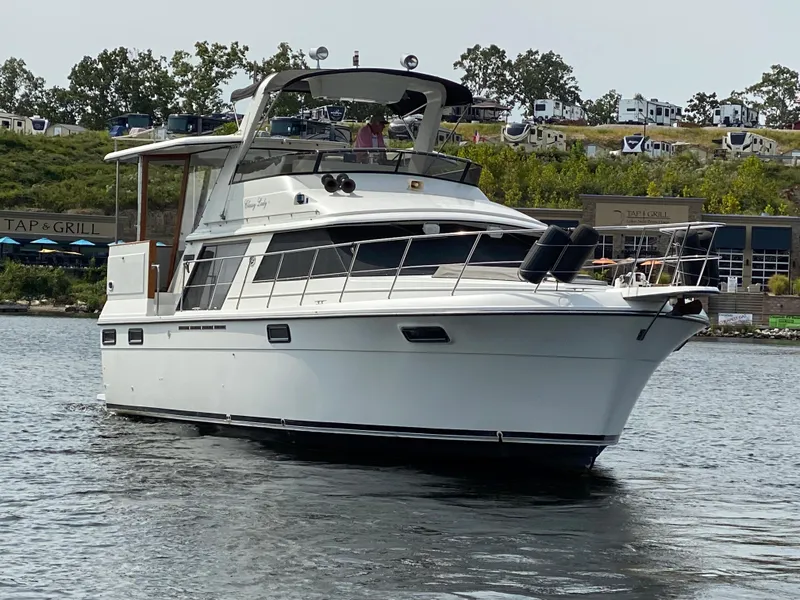 Slide: The Image of 1986 Carver 4207MY yacht cruising on a lake near a restaurant and RV park. - 5
