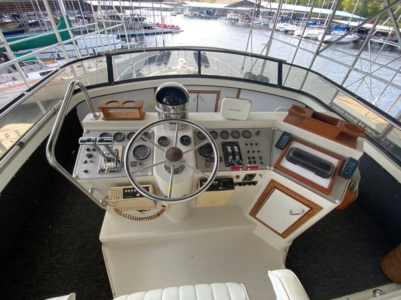 Slide: The Image of 1986 Carver 4207MY yacht helm with steering wheel, control panels, and marina view. - 45