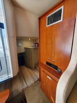 Slide: The Image of 2006 Rinker 300 Express Cruiser interior with wood cabinetry and cozy sleeping area. - 17