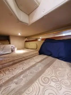 Slide: The Image of 2006 Rinker 300 Express Cruiser cabin with patterned bedding and ambient lighting. - 19