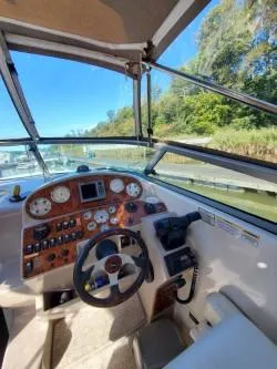 Slide: The Image of 2006 Rinker 300 Express Cruiser helm with gauges and steering wheel, dockside view. - 2