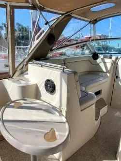 Slide: The Image of 2006 Rinker 300 Express Cruiser interior with seating and table, docked at marina. - 5