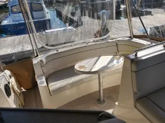 Slide: The Image of 2006 Rinker 300 Express Cruiser interior with seating and table, docked at marina. - 7