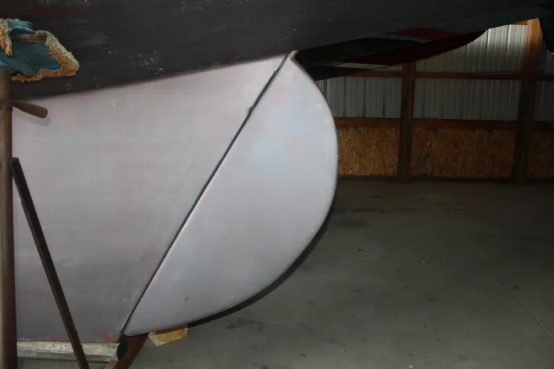 Slide: The Image of Close-up of the hull of a 1934 Custom Northern Michigan NM boat in a storage facility. - 13