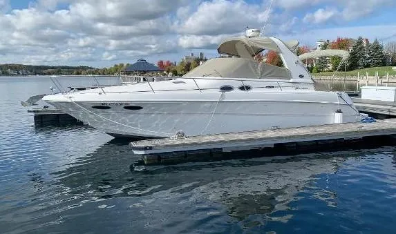 The Image of 2001 Sea Ray 310 Sundancer docked on a calm lake under a cloudy sky. - 0