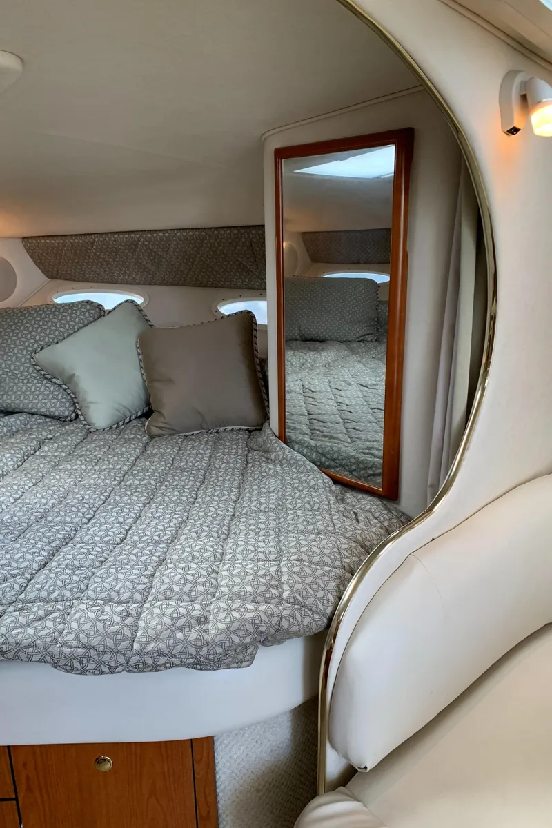 Slide: The Image of Interior cabin of 2001 Sea Ray 310 Sundancer with cozy bedding and mirror. - 16