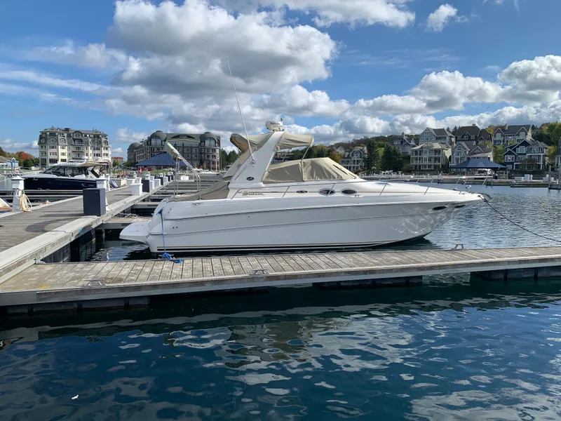 Slide: The Image of 2001 Sea Ray 310 Sundancer docked at a marina under a partly cloudy sky. - 2