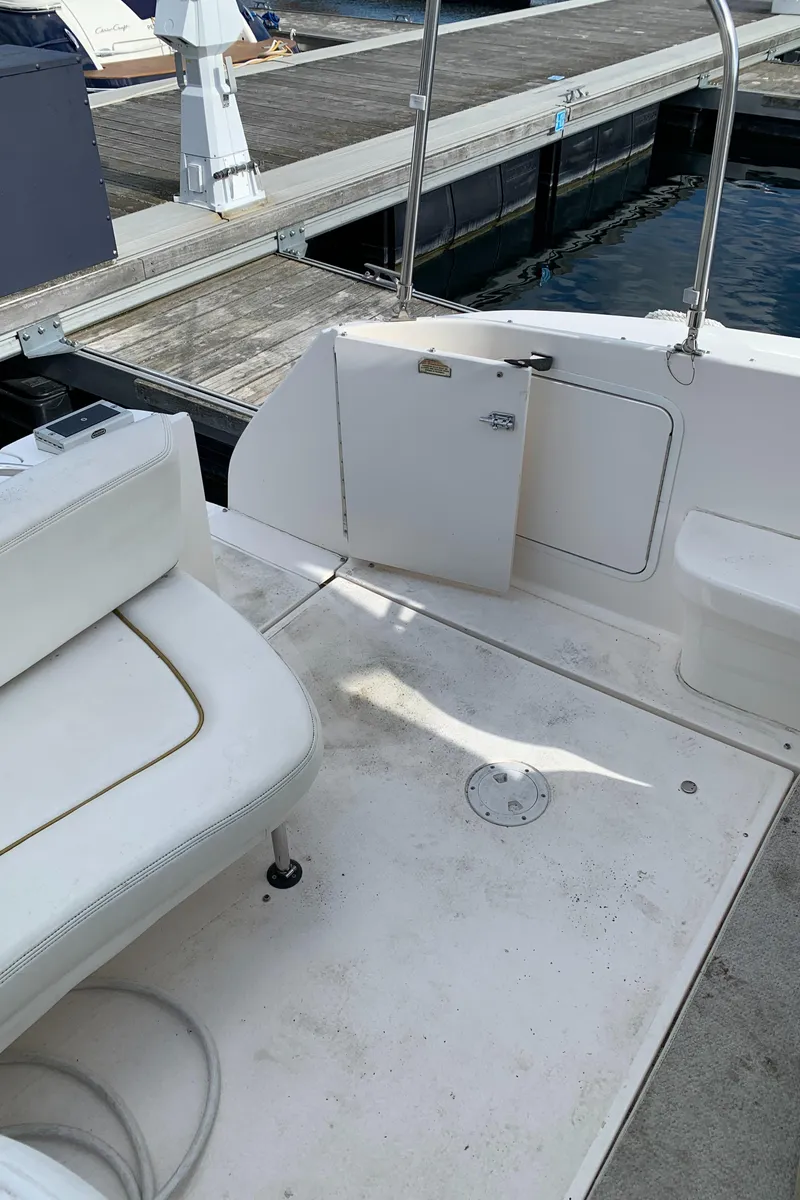 Slide: The Image of 2001 Sea Ray 310 Sundancer boat interior at dock, featuring white seating and open hatch. - 24