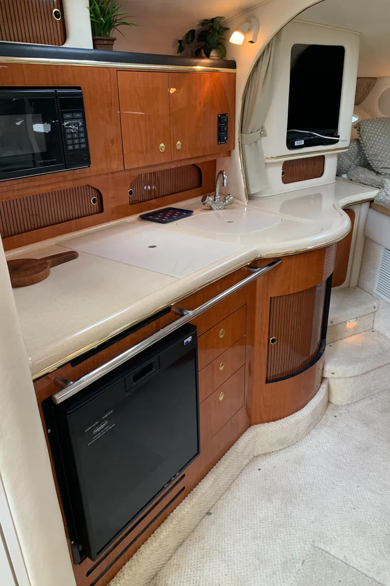 Slide: The Image of 2001 Sea Ray 310 Sundancer interior kitchen with wood cabinetry and modern appliances. - 9