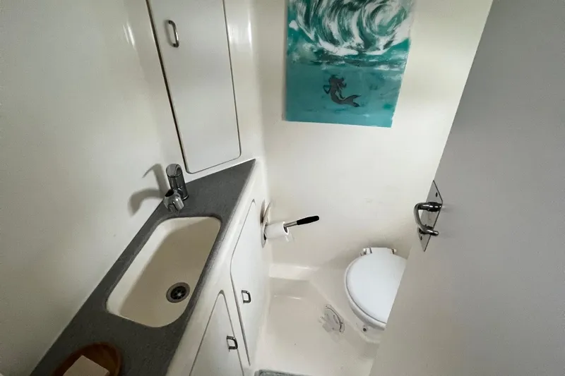 Slide: The Image of Compact bathroom in a 1996 Voyage Yachts 470, featuring a sink, toilet, and storage cabinets. - 42