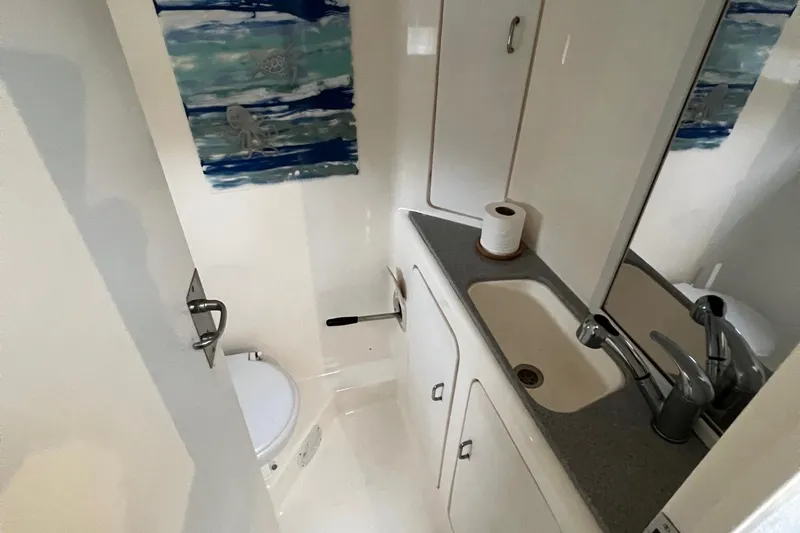 Slide: The Image of Compact bathroom in a 1996 Voyage Yachts 470, featuring a sink, toilet, and storage cabinets. - 44