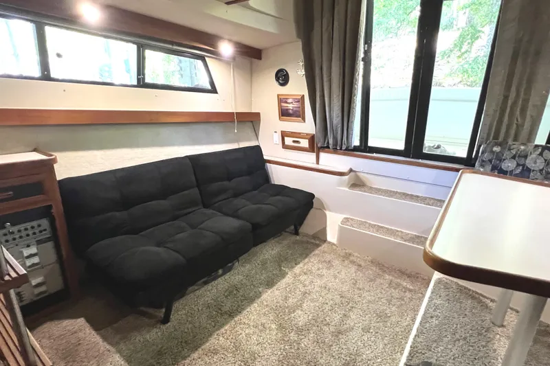Slide: The Image of 1989 Carver 32 Mariner interior with black sofa, carpeted floor, and large windows. - 20