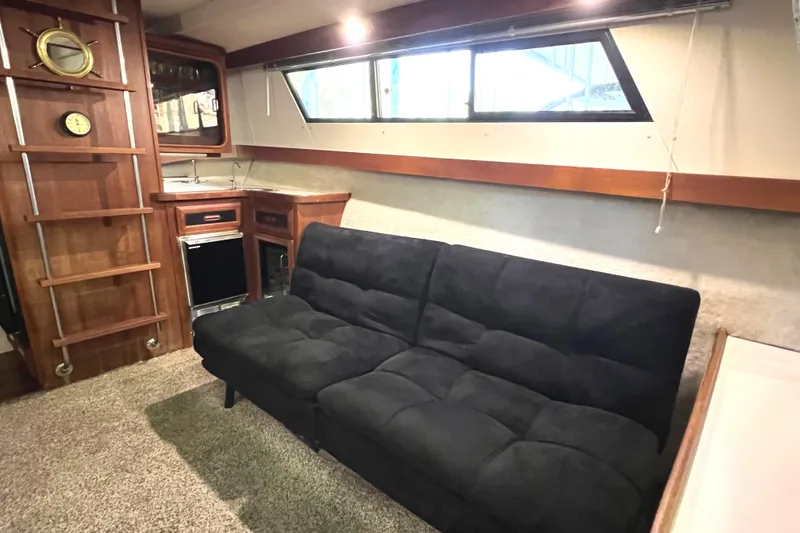 Slide: The Image of 1989 Carver 32 Mariner interior with black sofa, wooden cabinetry, and nautical decor. - 21