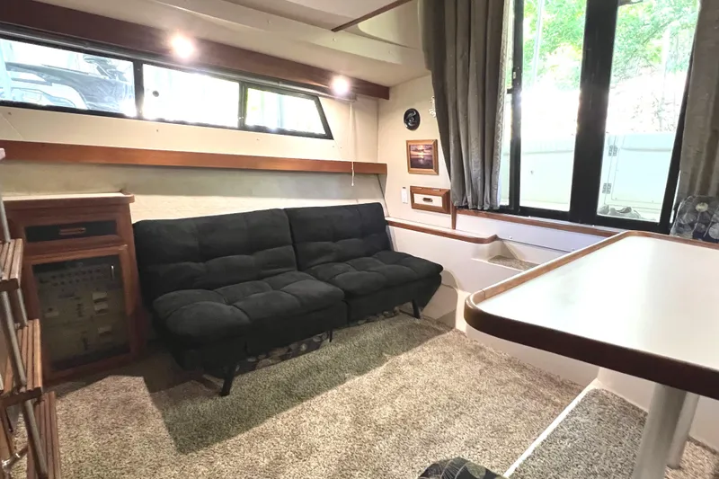 Slide: The Image of 1989 Carver 32 Mariner interior with black sofa, carpeted floor, and large windows. - 22