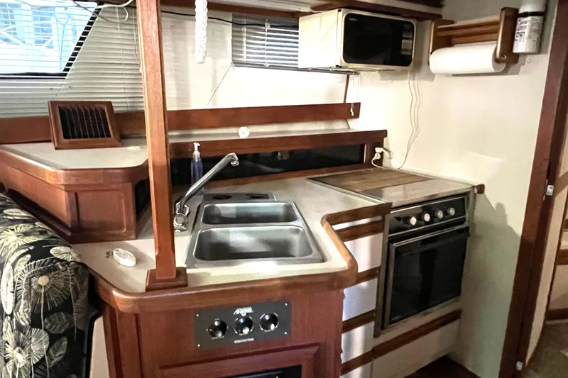 Slide: The Image of 1989 Carver 32 Mariner kitchen with sink, stove, and microwave in a compact layout. - 25