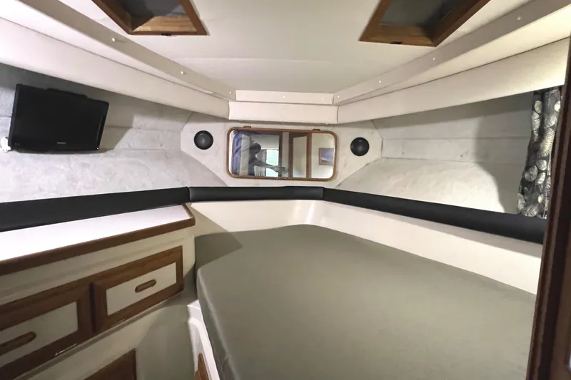 Slide: The Image of 1989 Carver 32 Mariner cabin interior with bed, storage, and TV. - 26