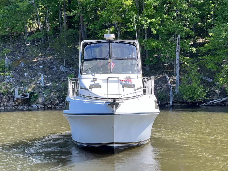 Slide: The Image of 1989 Carver 32 Mariner boat on a calm lake with forested background. - 3