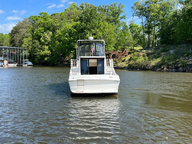 Slide: The Image of 1989 Carver 32 Mariner boat on a calm river, surrounded by lush greenery. - 5