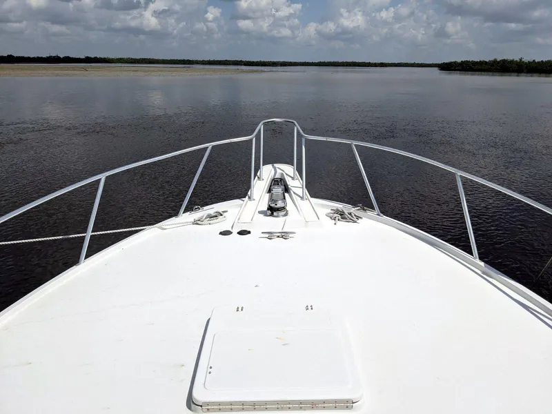 Slide: The Image of Bow view of 1977 Hatteras 46 Convertible yacht on calm water under cloudy sky. - 9