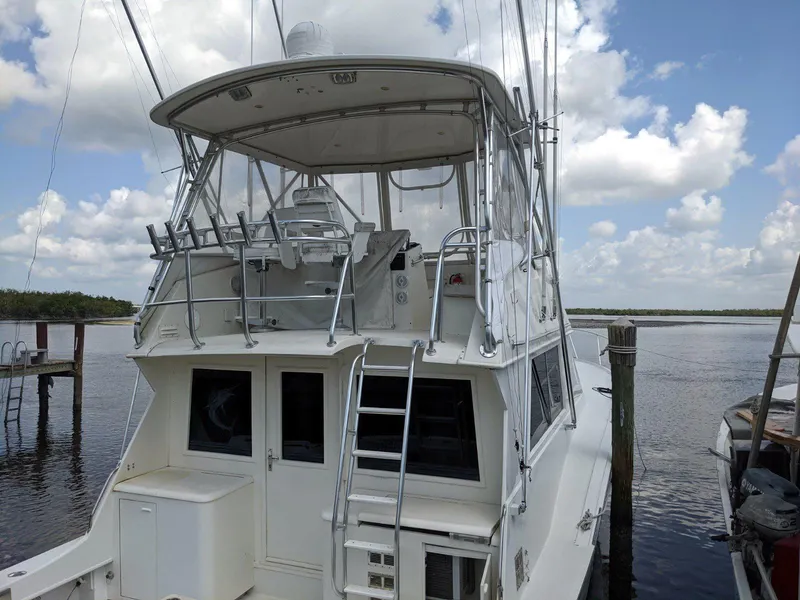 Slide: The Image of 1977 Hatteras 46 Convertible yacht docked under a cloudy sky. - 2