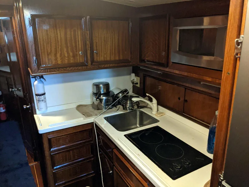 Slide: The Image of 1977 Hatteras 46 Convertible yacht kitchen with wooden cabinets, sink, stovetop, and microwave. - 20