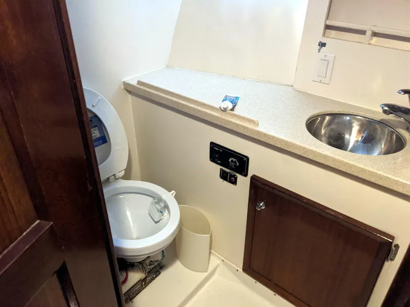 Slide: The Image of 1977 Hatteras 46 Convertible yacht bathroom with toilet, sink, and storage cabinet. - 26