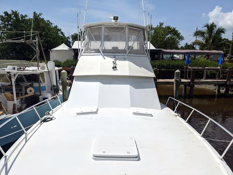 Slide: The Image of 1977 Hatteras 46 Convertible yacht docked, featuring spacious deck and flybridge under clear skies. - 8