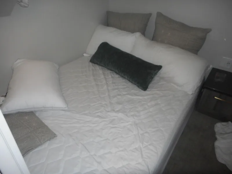 Slide: The Image of Cozy bedroom with neatly arranged pillows on a white quilted bedspread, Adonia Melody Share #12. - 26