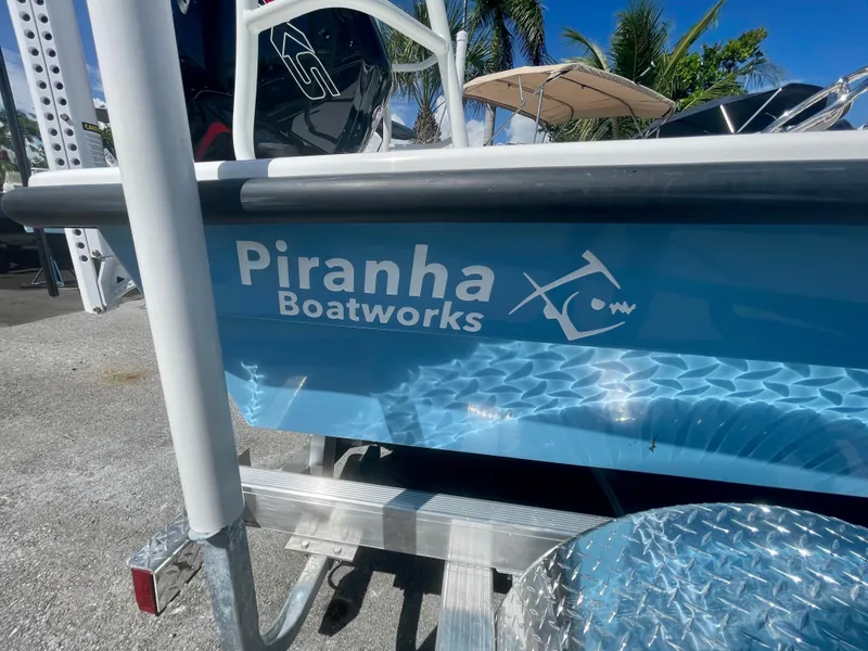 Slide: The Image of Piranha Magro P180 boat, 2025 model, with logo, parked outdoors under clear sky. - 22