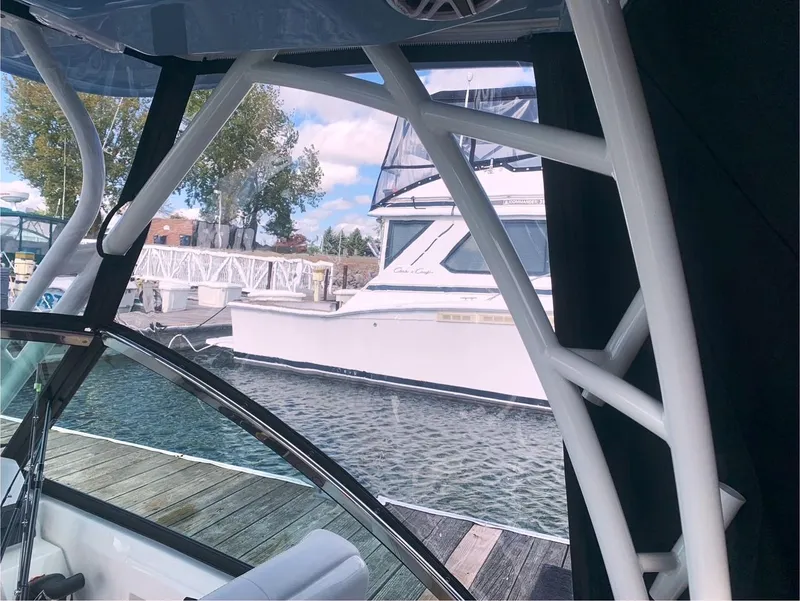 Slide: The Image of 2022 Cobia 240 DC boat docked, view from interior, with marina and another boat visible. - 10