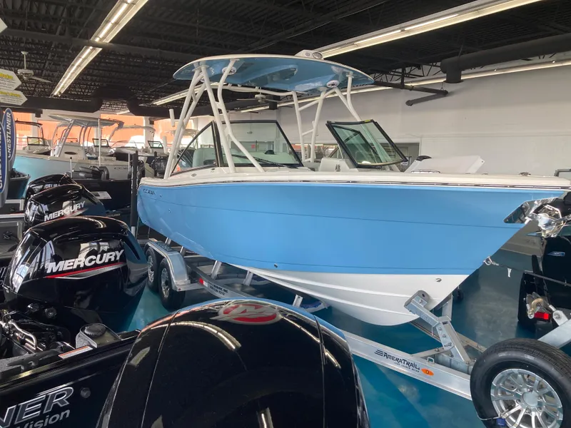 Slide: The Image of 2022 Cobia 240 DC boat in showroom, blue and white, on trailer. - 13