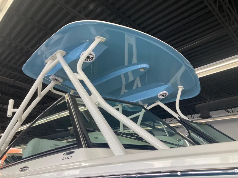 Slide: The Image of 2022 Cobia 240 DC boat with blue hardtop and white supports in showroom. - 17