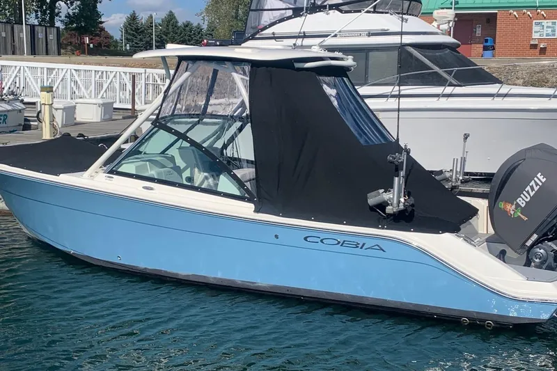 Slide: The Image of 2022 Cobia 240 DC boat docked, featuring a sleek design and blue hull. - 2