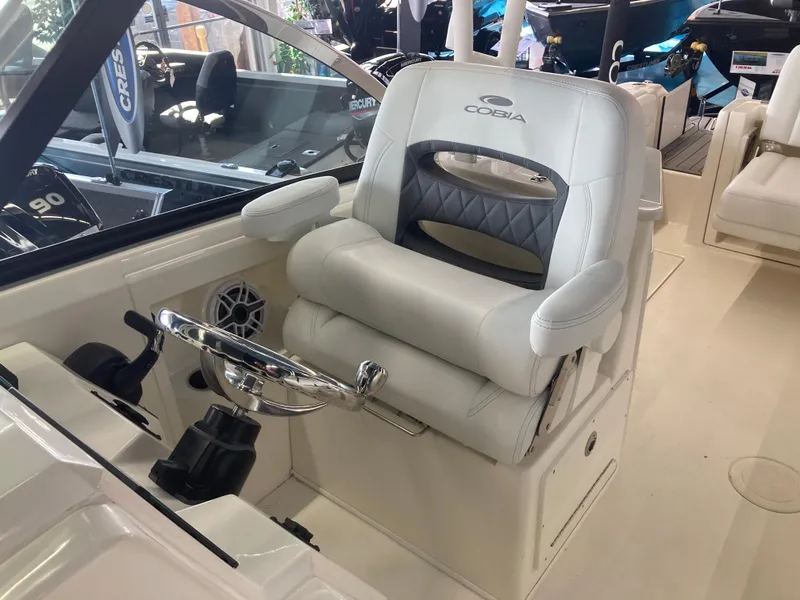 Slide: The Image of Captain's seat of a 2022 Cobia 240 DC boat, featuring a sleek design and steering wheel. - 25