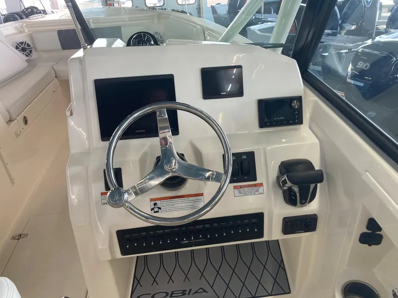 Slide: The Image of 2022 Cobia 240 DC boat dashboard with steering wheel and control panel. - 28