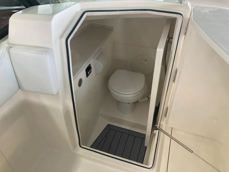 Slide: The Image of 2022 Cobia 240 DC boat interior with compact marine toilet and storage space. - 30