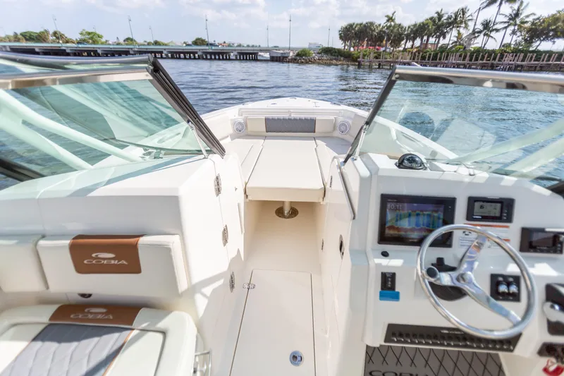 Slide: The Image of 2022 Cobia 240 DC boat interior with steering wheel and seating, on a sunny day. - 32