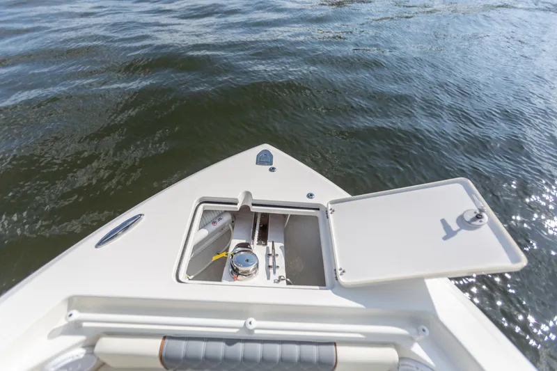 Slide: The Image of 2022 Cobia 240 DC boat bow with open storage compartment on calm water. - 34