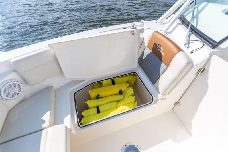 Slide: The Image of 2022 Cobia 240 DC boat with open storage compartment containing yellow life jackets. - 38