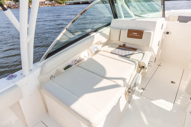 Slide: The Image of 2022 Cobia 240 DC boat interior with comfortable seating, white upholstery, and scenic water view. - 39